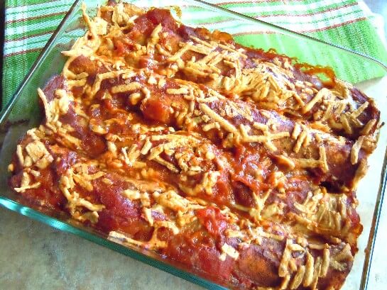 Baked Gringo Enchiladas all lined up in a clear casserole against a green mat.
