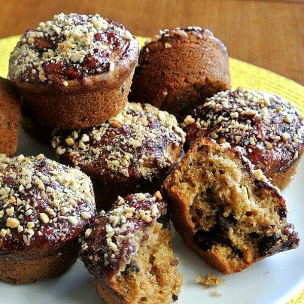 A pile of muffins with a jelly and nut topping on a white.