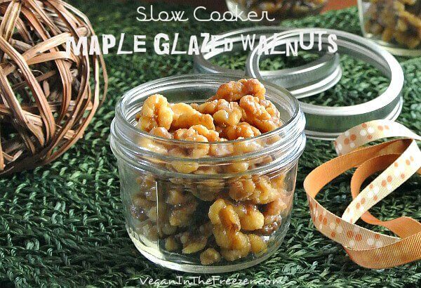 Half pint jar full of candied walnuts on a green woven mat with ribbon on the side.