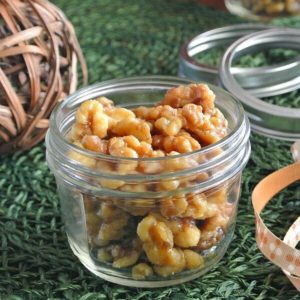 Slow Cooker Maple Glazed Walnuts are in a canning jar with ribbon on the side so that it can be wrapped for a holiday gift.
