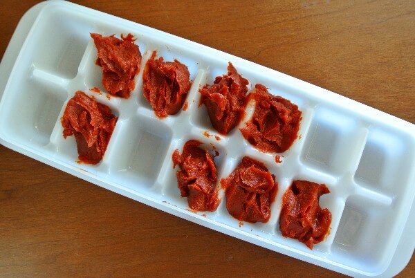 Tomato Paste is divided by tablespoons in a ice cube tray for freezing