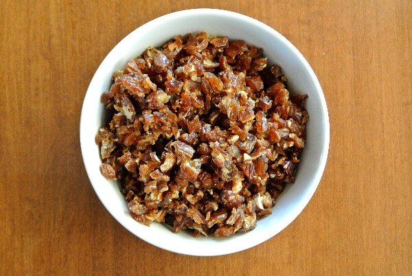 Overhead view of chopped dates in a white bowl.