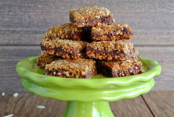 A close-up of the Best date Bars stacked high on a green compote dish.