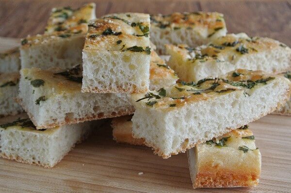 Herbed Focaccia with a close up of long fat and narrow slices that would be perfect for biting or dunking.