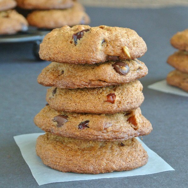 A stack of 5 cookies on a parchment paper square with all of the extra chip ingredients.