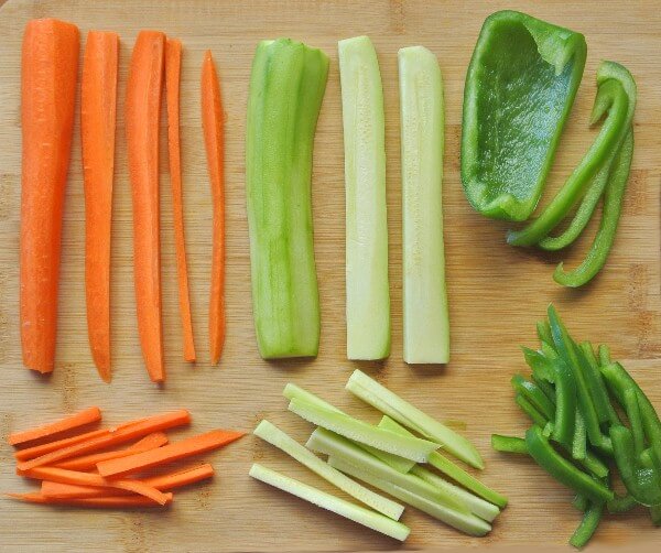 Rainbow Veggie Hash Brown Potatoes and laying on a wooden cutting board and cut into their groups of julliened pieces.