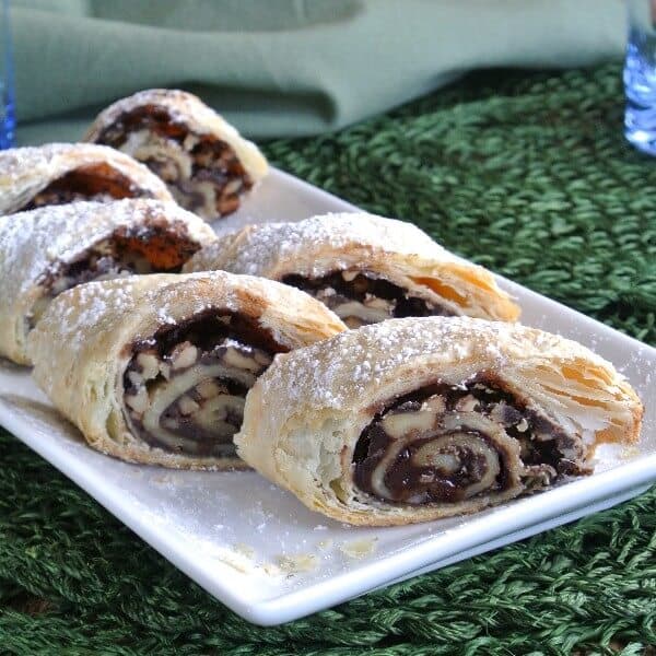 Chocolate Strudel is sliced and laid out on a white rectangle plate. Green mat under all.