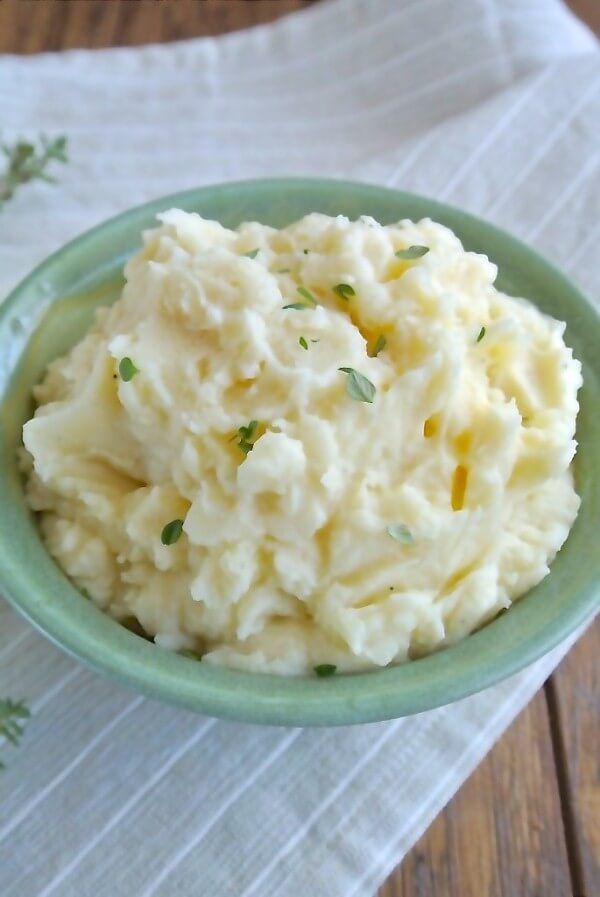 Slow Cooker Mashed Potatoes at an overhead view of a pale green pottery bowl full of soft creamy mashed potatoes.