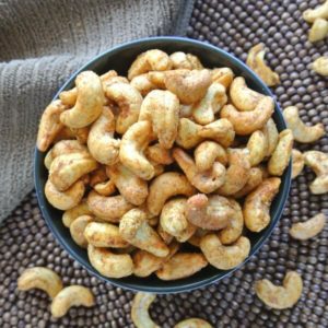A gorgeous closeup photo of whole cashews with dark rich spices baked in and clinging to the sides.