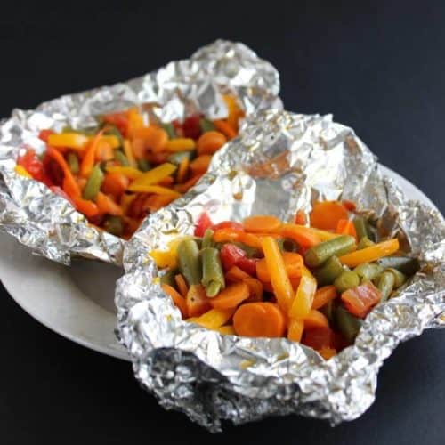 Small snapped and sliced vegetables areare piled high in an open foil package.