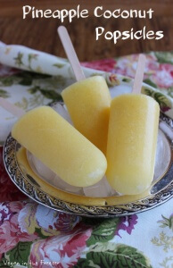 Pineapple Coconut Popsicles are laying on a silverplate tray - three to a bunch and of in the color sunny yellow.