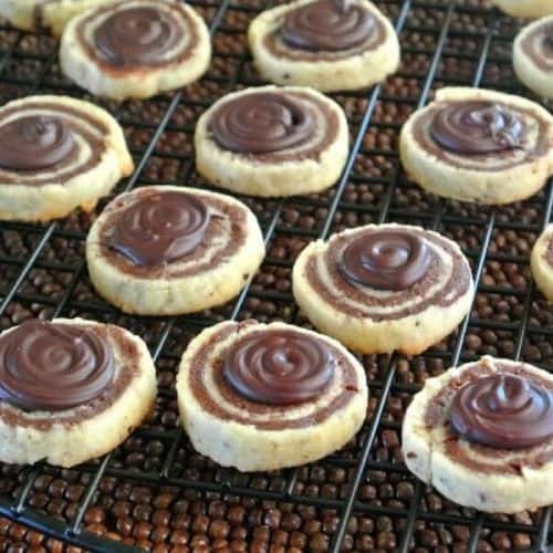 Chocolate Pinwheels with a chocolate swirl topping and sitting on a wire rack.