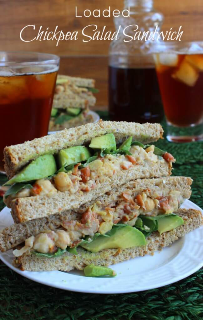Loaded Chickpea Salad Sandwich is cut in half and stacked double high. Soft wheat bread avocado and chickpea salad are thickly layered.