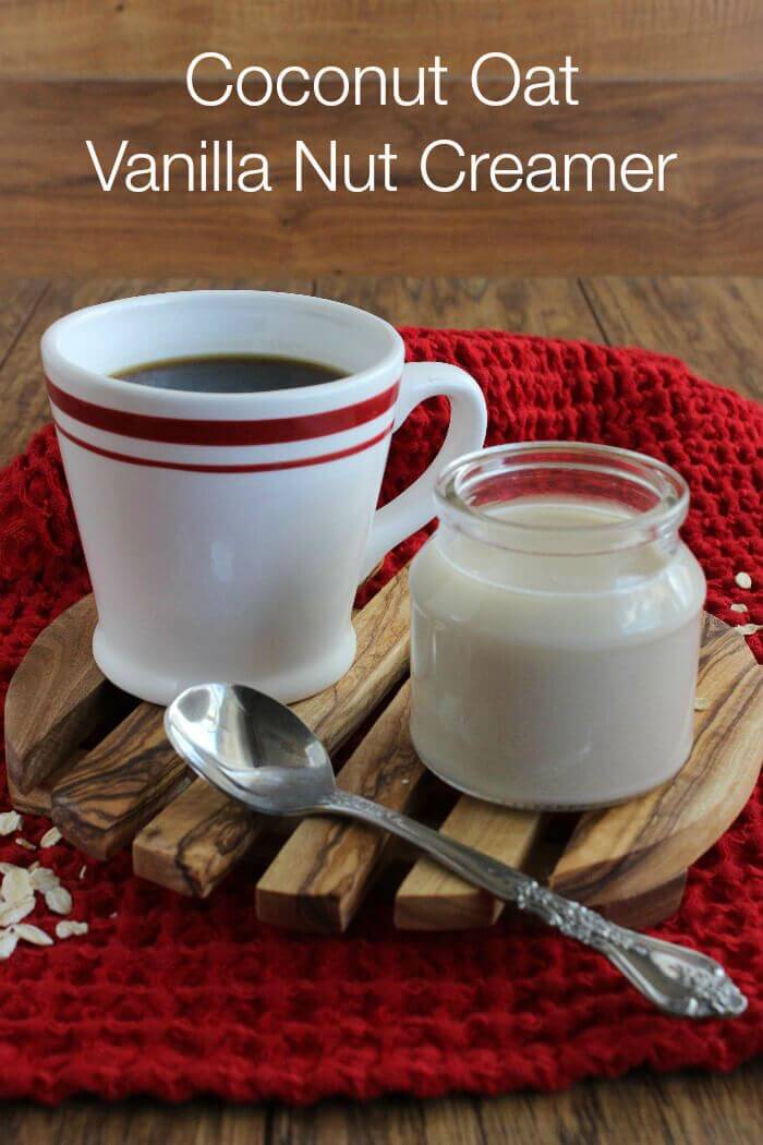 Coconut Oat Vanilla Nut Creamer is in a small jar with a full cup of coffee alongside with a red hand towel.