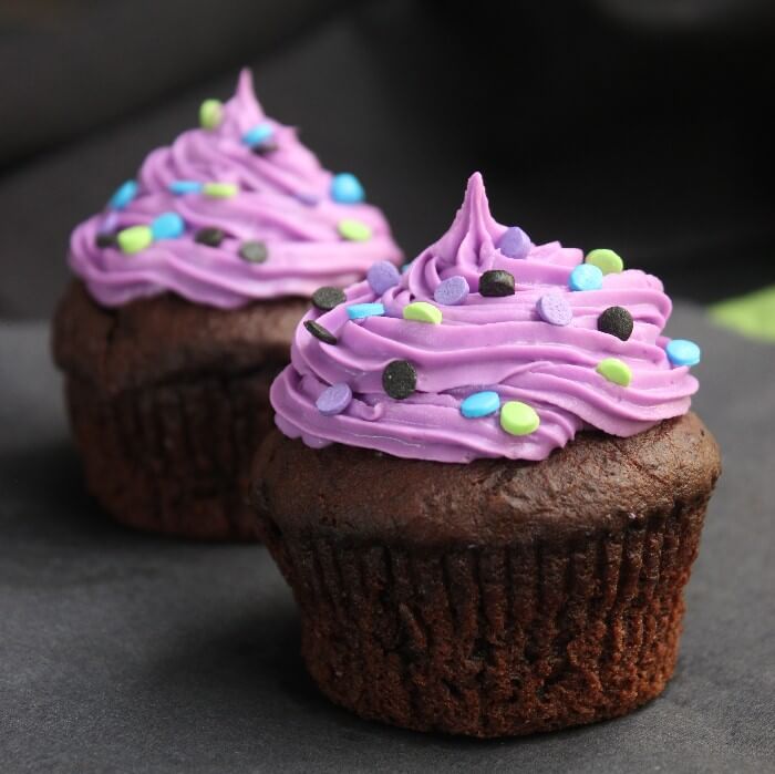 Halloween Chocolate Lava Cupcakes have beautiful Halloween colors with bright purple frosting and lime green, brown, and turquoise sprinkles.