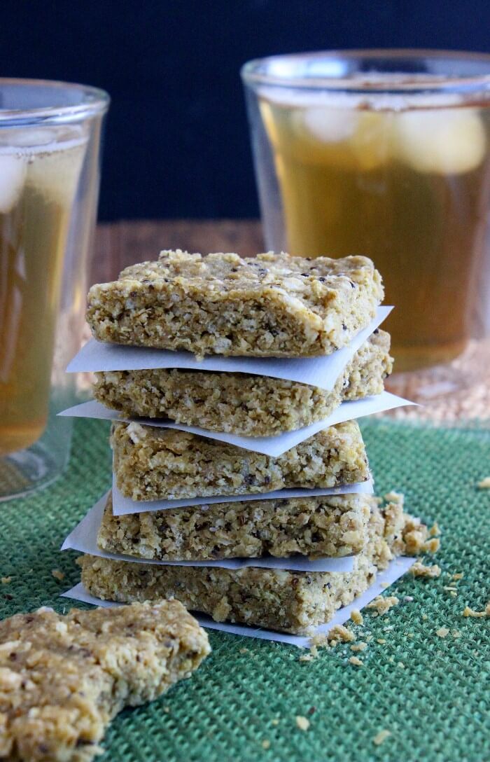 Almond Butter Protein Bars are stacked squares, five high. Two glasses of ices tea are sitting behind.