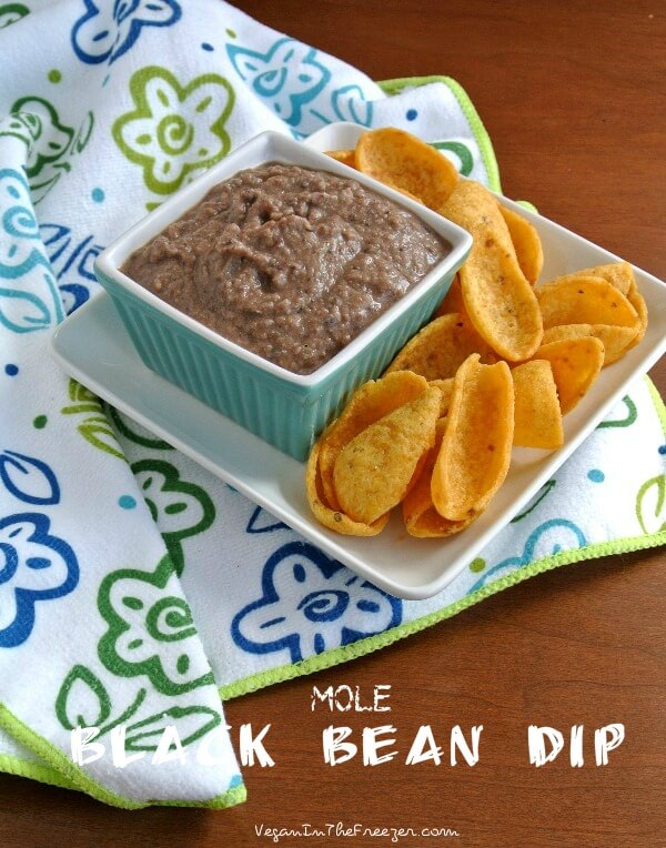 An angled square blue bowl filled with a spread and served with giant fritos.