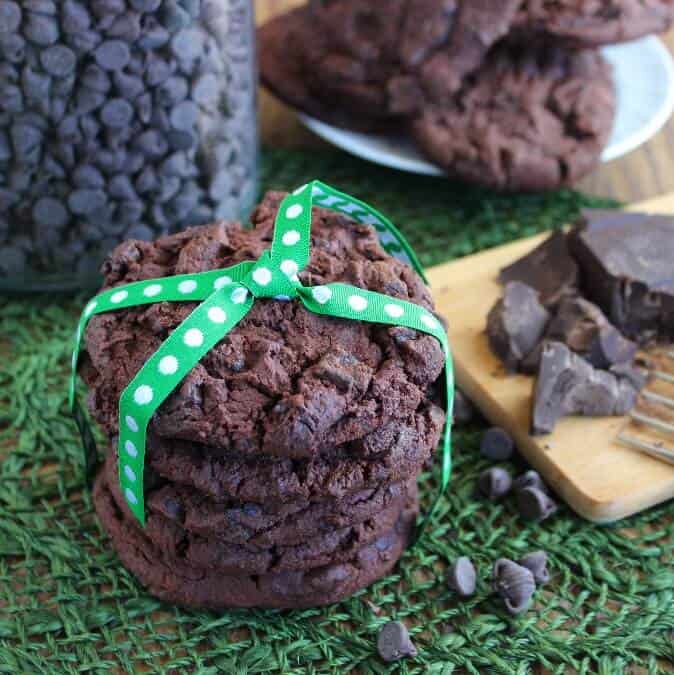 Triple Chocolate Cookies are tied up in a green cloth ribbon on a woven mat.