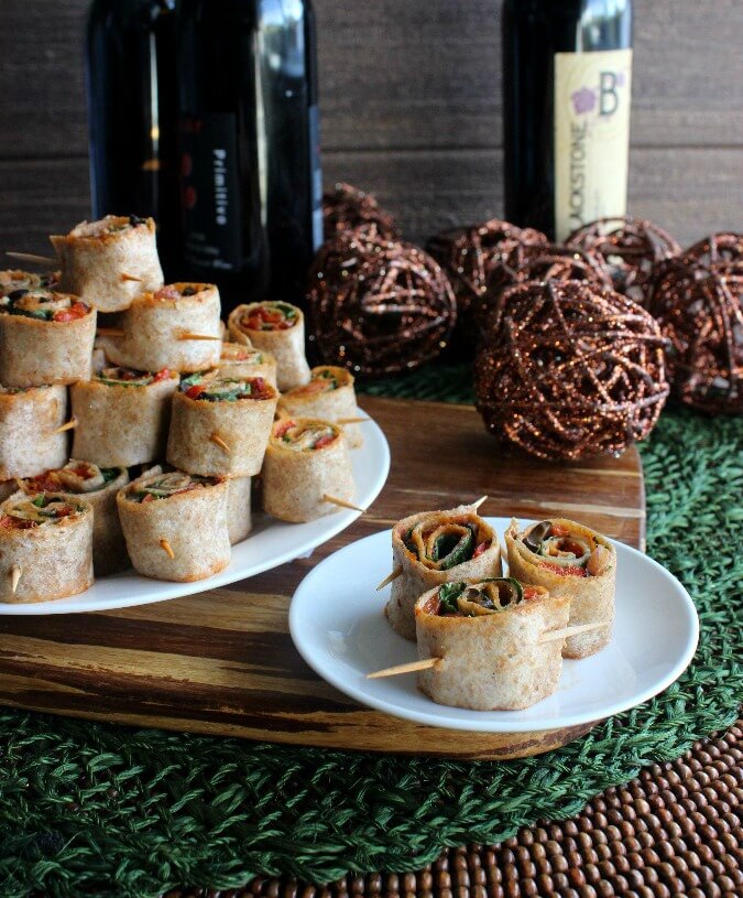 Spicy Tortilla Rollups are stacked as a pyramid surrounded with dark earthy background colors and napkins on the side.