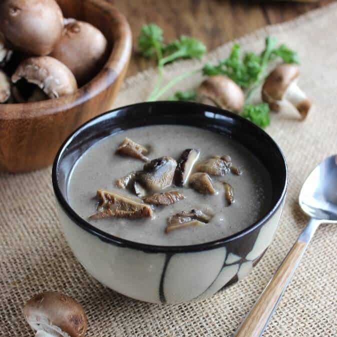 An Asian designed bowl is filled with creamy mushroom soup and garnished with wild mushroom slices.