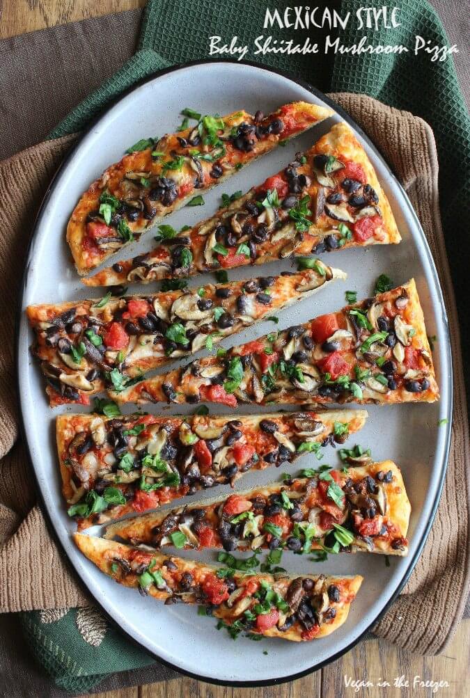 Full enamelware platter showing and oval mushroom pizza sliced horizontally on a dough that is a break machine pizza dough.