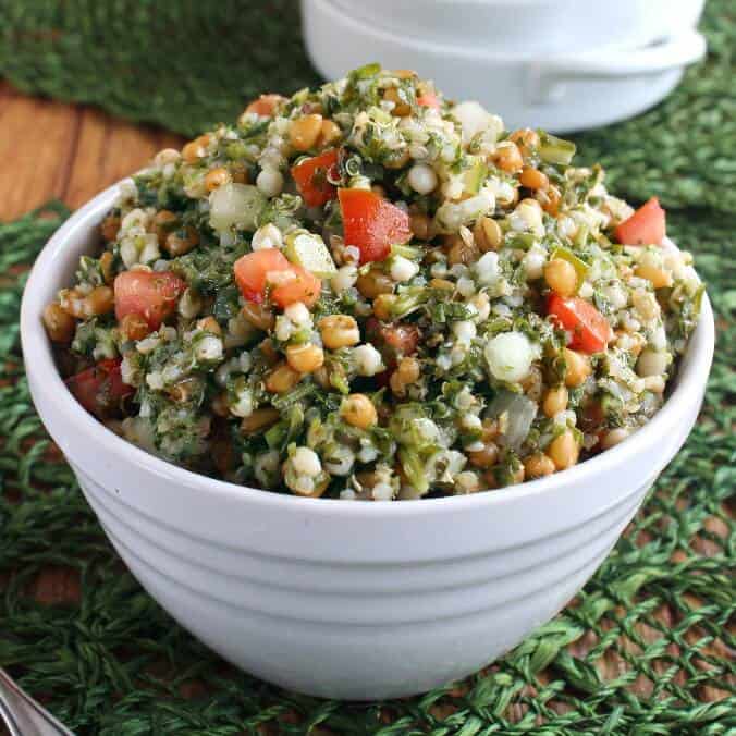 Taboule is piled high in a serving bowl on a green mat.