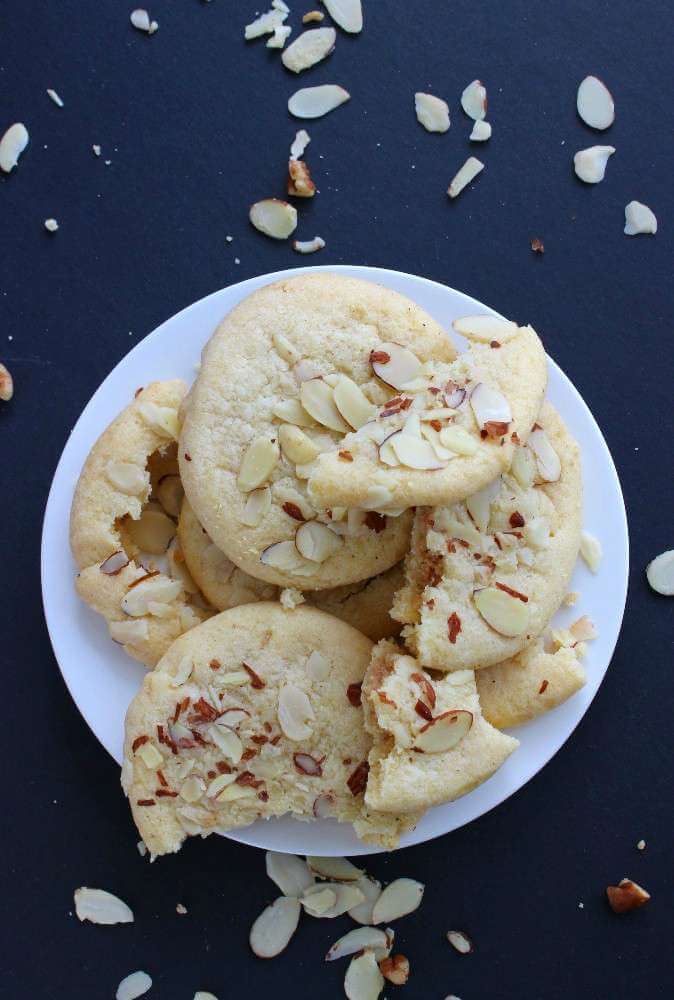 Chinese Almond Butter Cookies are viewed from overhead with slivered almonds scattered around.