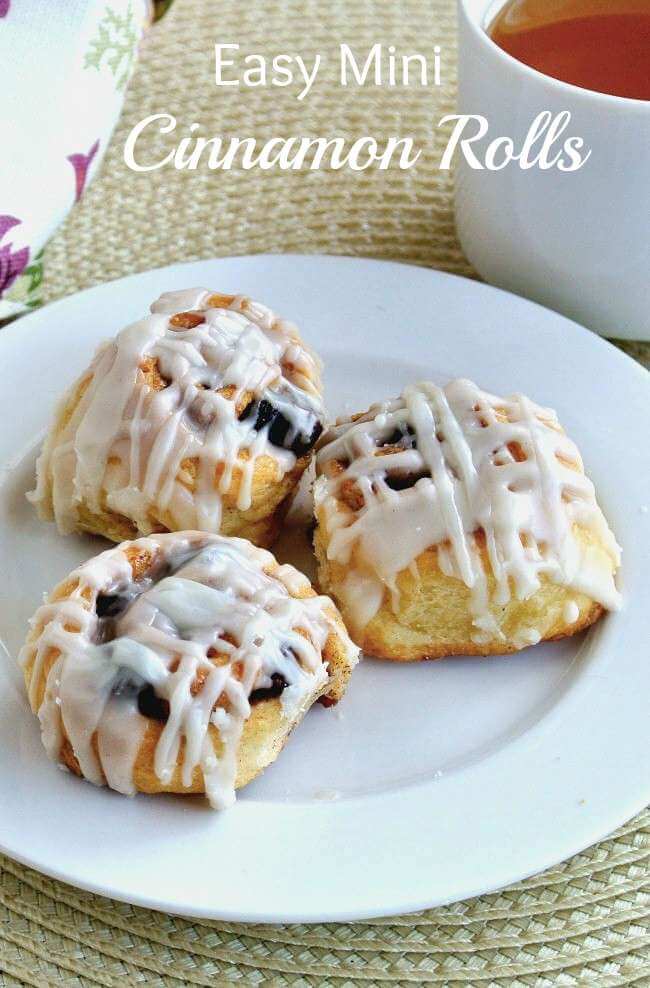 Three mini cinnamon rolls on a white plate with crosshatch icing on the tops.