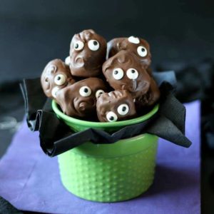 Chocolate cover candy bars in a green bowl with a black tissue poking out below. Added candy eyes for fun!.