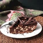 A sideways view of chocolate pie in a chocolate crust with walnuts and shaved chocolate on top.