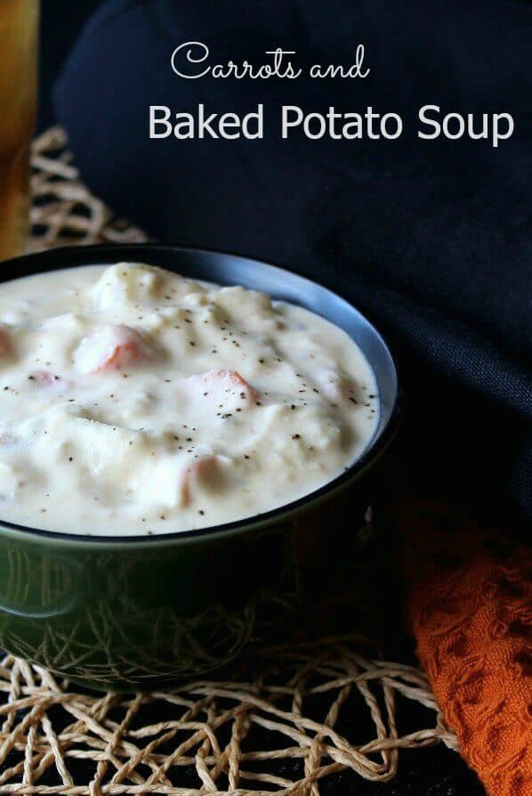 Thick soup is filling a green bowl with creamy potatoes and carrot soup. Sittinf on a open weave mat and fading out to black in the background.