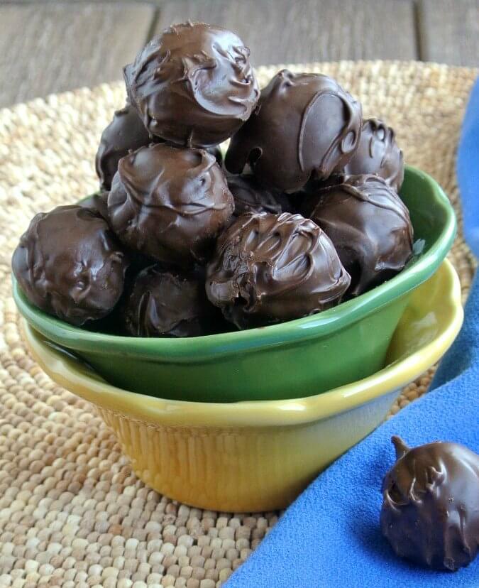 Glistening chocolate balls piled high in a green bowl. Centered for the photo.