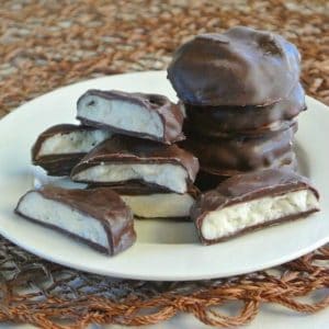 Homemade Peppermint Patties are stacked high and tilted forward on a small white plate.