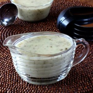 Vegan White Pizza Sauce is in a clear glass ridged creamer with more sauce and a scoop behind.