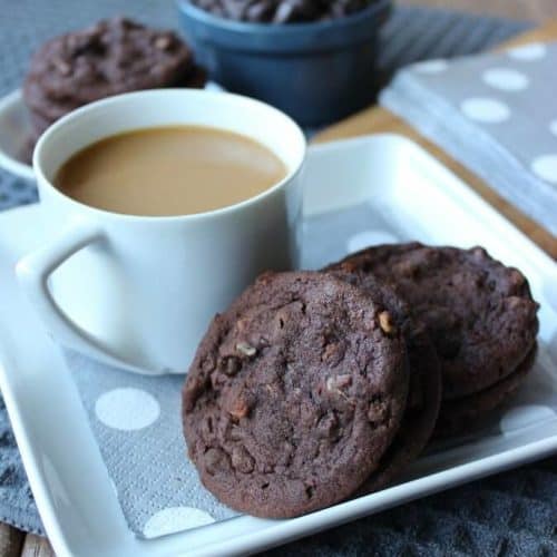 Irish Cream Chocolate Cookies are on a square white plate with a silver polka dot napkin underneath with a cup of coffee on the side.