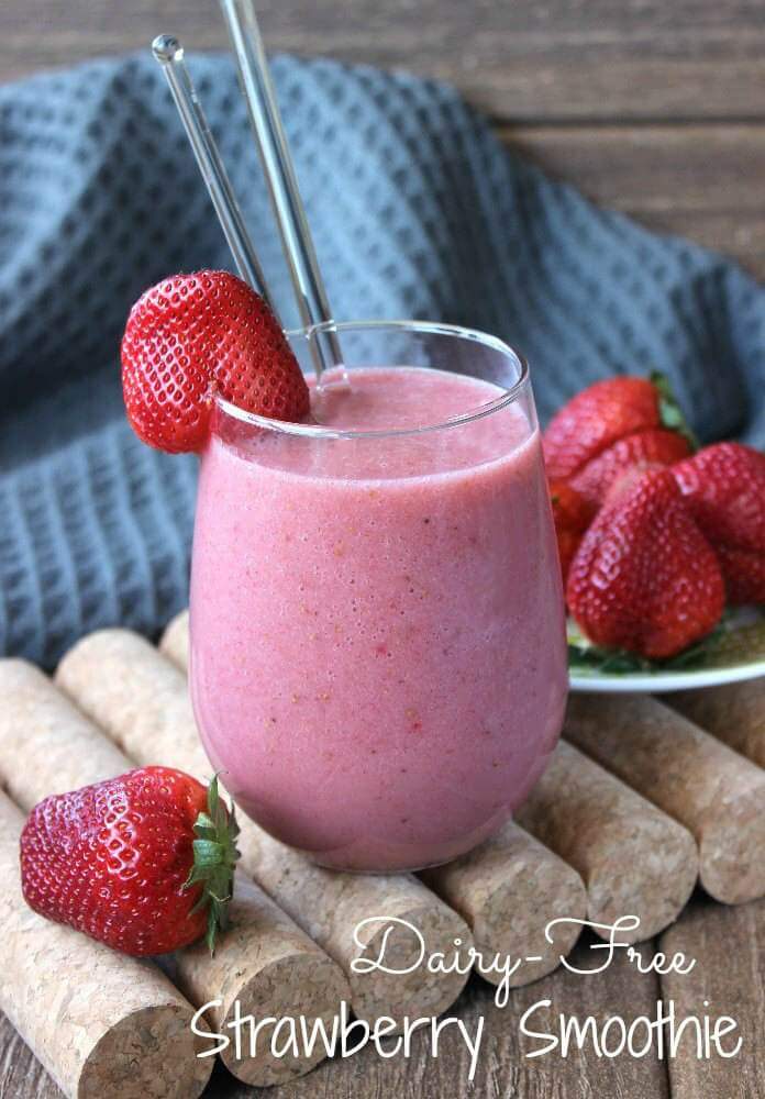 El Batido de Fresa sin Leche es de color rosa brillante en un vaso redondo con una fresa en el borde para decorar.