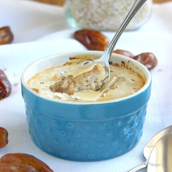 A thick oats creme brulee is sitting in a small turquoise bowl and has a hard shell sugar topping.