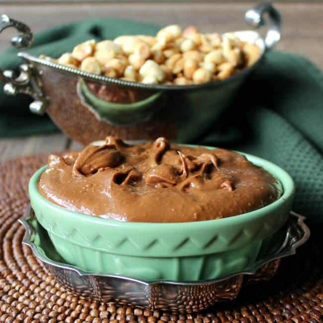 Clean Chocolate Peanut Butter filled and peaked in a low wide green bowl sitting on a silver plated trivet.