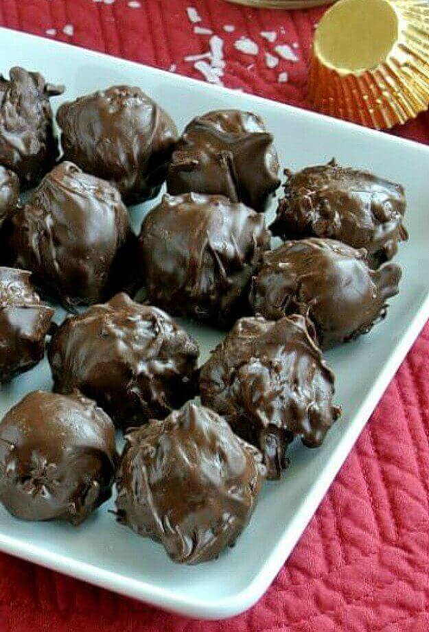 Chocolate Mounds Candy thickly coated in chocolate and placed in perfect rows on a white square plate. Set against a bright red mat.