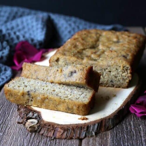 A gluten free loaf on a wood slab cutting board with two slices off the front to show you the center.