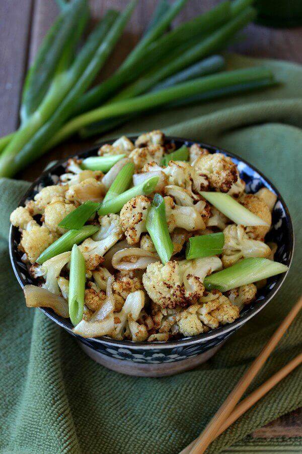 Air Fried Spicy Cauliflower Stir-Fry at an above head angle. A full bowl is filled with the dish on a green cloth with chopsticks at the side.