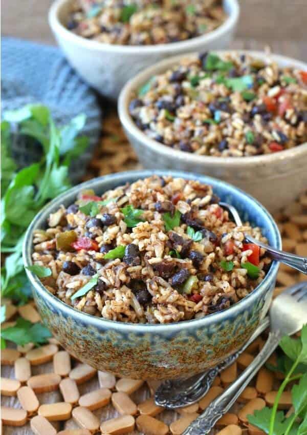 Acadian Black Beans and Rice are mixed together with beautiful beiges, blacks and reds then sprinkled with green parsley. All piles in a blue speckles bowl.