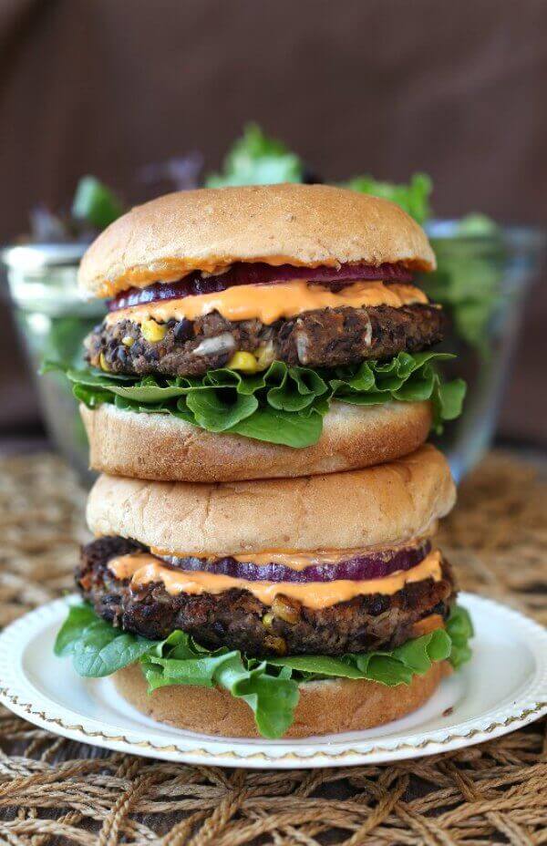 Black Bean Burgers Recipe sitting tall with a double stack and dressed for eating.