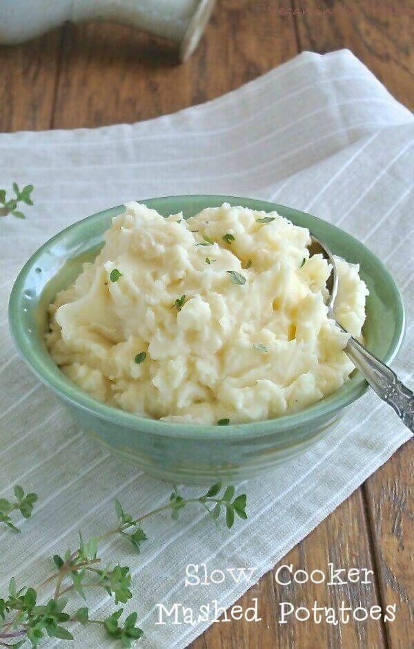 Slow Cooker Mashed Potatoes in a pale green pottery bowl over beige linen napkin.