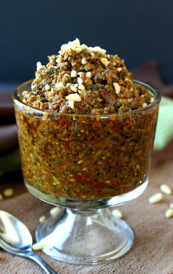  Vegan Sun Dried Tomato Pesto is overflowing in in a small footed glass dish.
