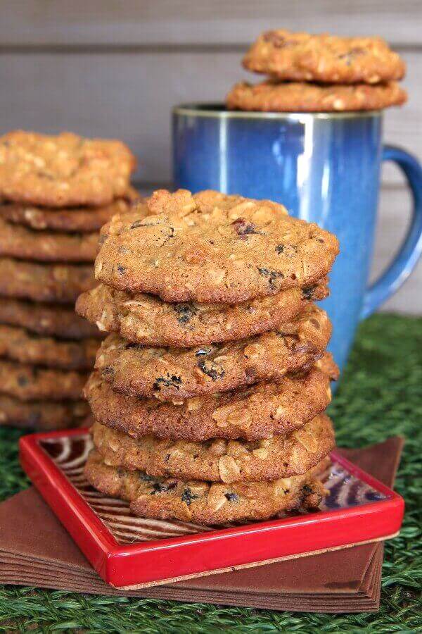 Cranberry Orange Cookies are stacked high on a coaster with coffee behind.