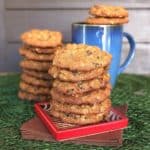 Orange Cranberry Cookies are stacked six cookies high on a red square coaster with another stack behind.