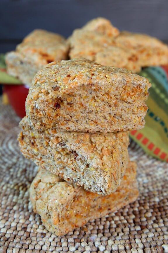Chipotle Scones are speckled with orange dairy free cheese and red chipotle bits. Stacked three high.
