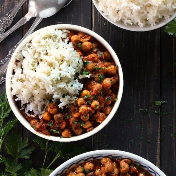 Recette de curry de pois chiches à cuisson lente avec une vue aérienne d'un bol plein de curry riche en sauce rouge avec du riz blanc au jasmin.