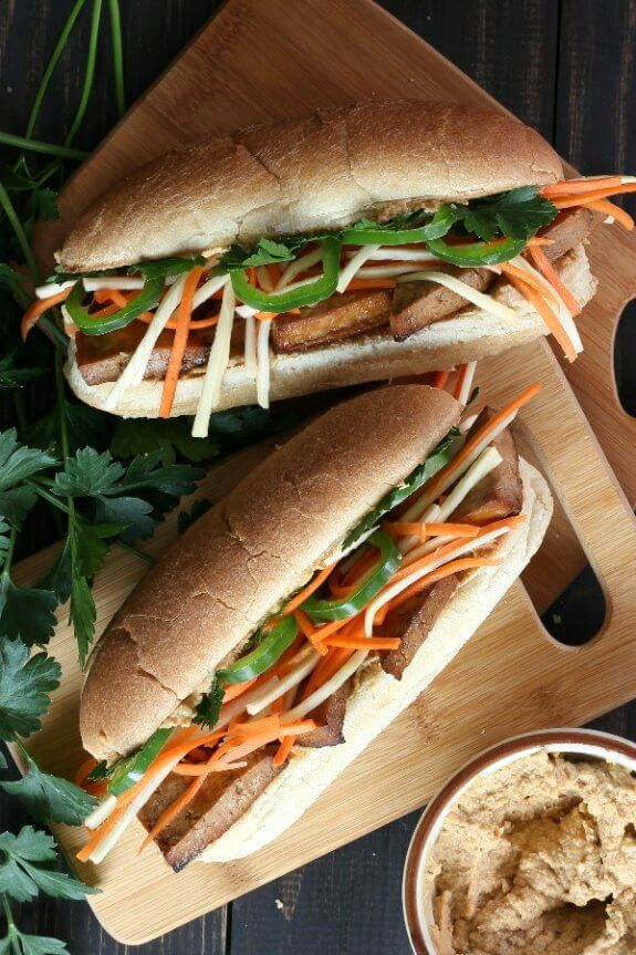 Two Long Sub Rolls laying on their back with layers of golden baked tofu with julienned carrots and parsnips and jalepenos.